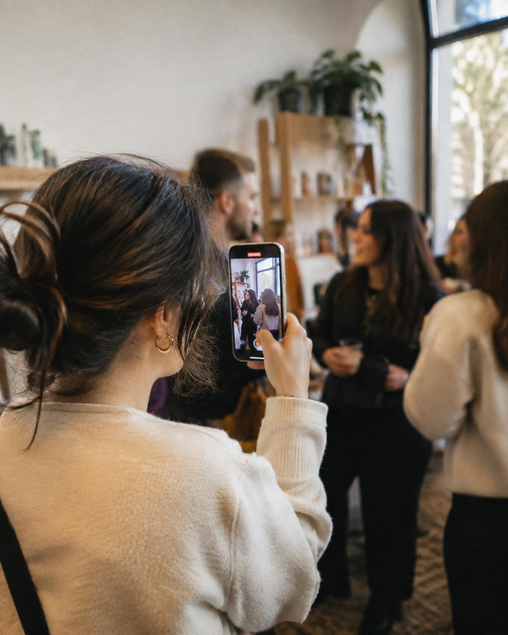 Pessoa a gravar vídeo vertical com smartphone durante um pequeno evento de marca